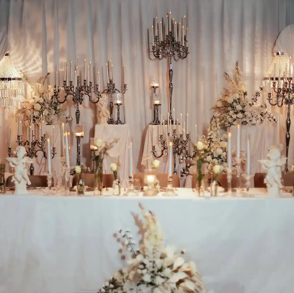 Layered candelabra and candleholder wedding stage Wedding stage decorated with multi-head candelabras and glass candleholders at several heights