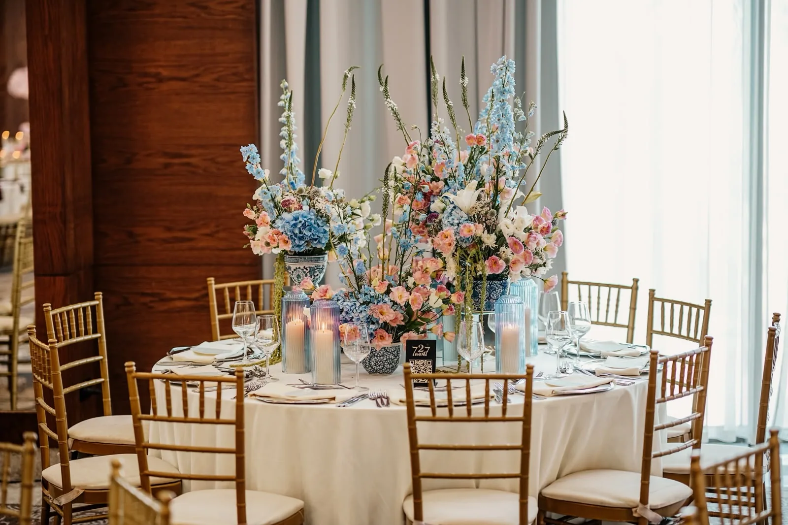 Pastel çiçekler ve cam mumluklarla hazırlanmış yuvarlak otel düğün masası